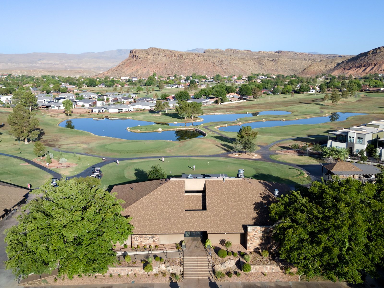 Aerial of a country club clubhouse, golf course, and red rock mesas
