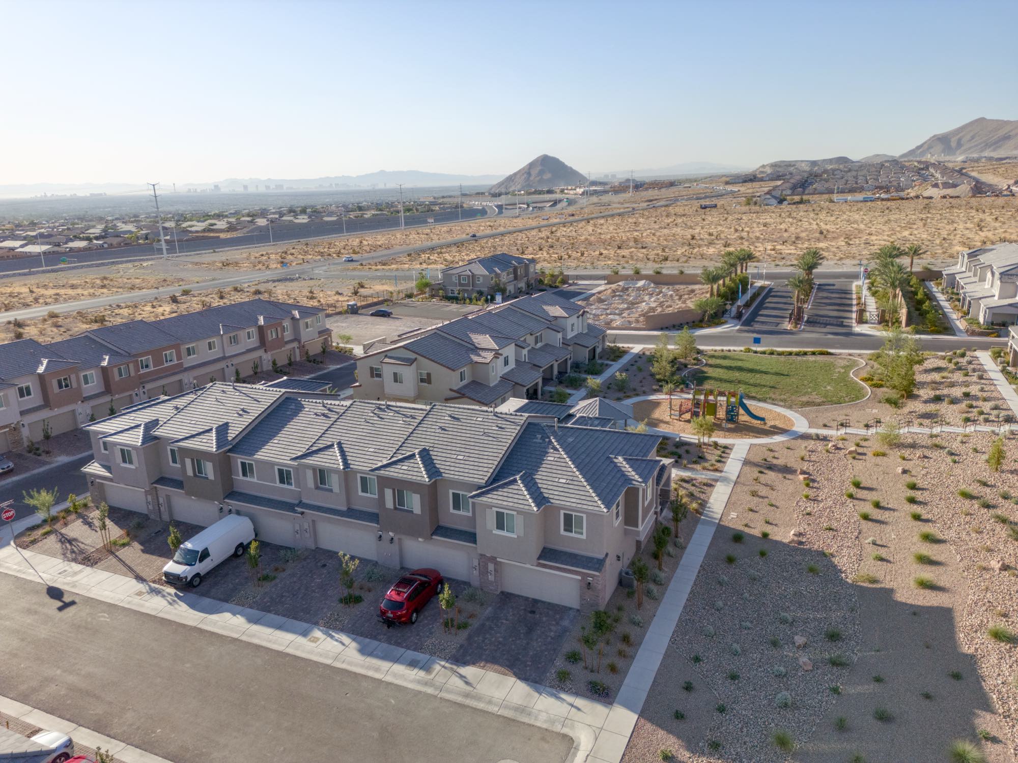 Low aerial of a Lennar townhome block at Centennial Heights with the community park and the Las Vegas valley beyond