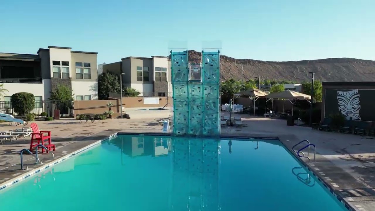A translucent climbing structure standing in the pool at Bloomington Country Club, St. George, Utah, with red rock behind